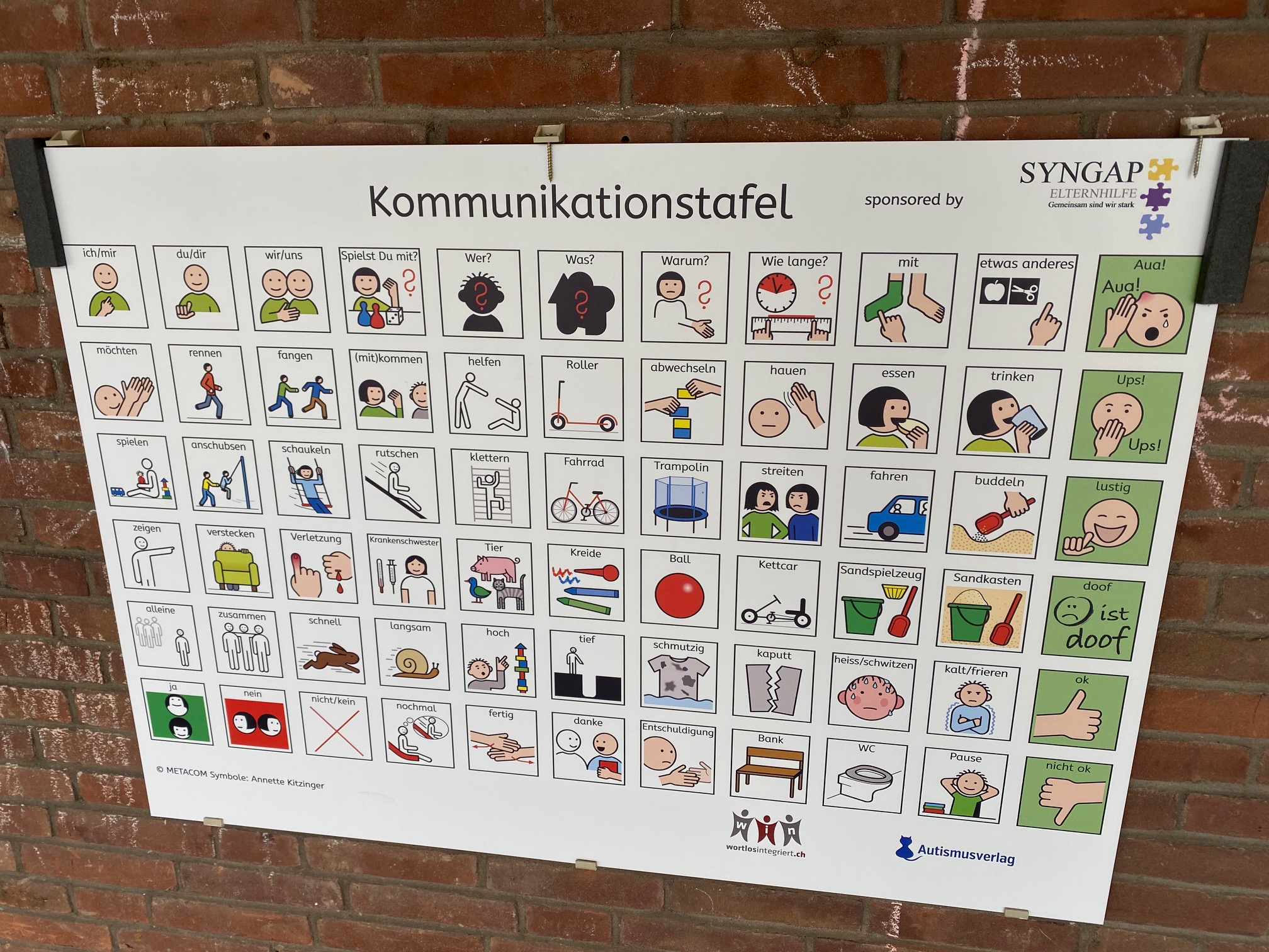 Spielplatztafel mit METACOM Symbolen an Ziegelmauer