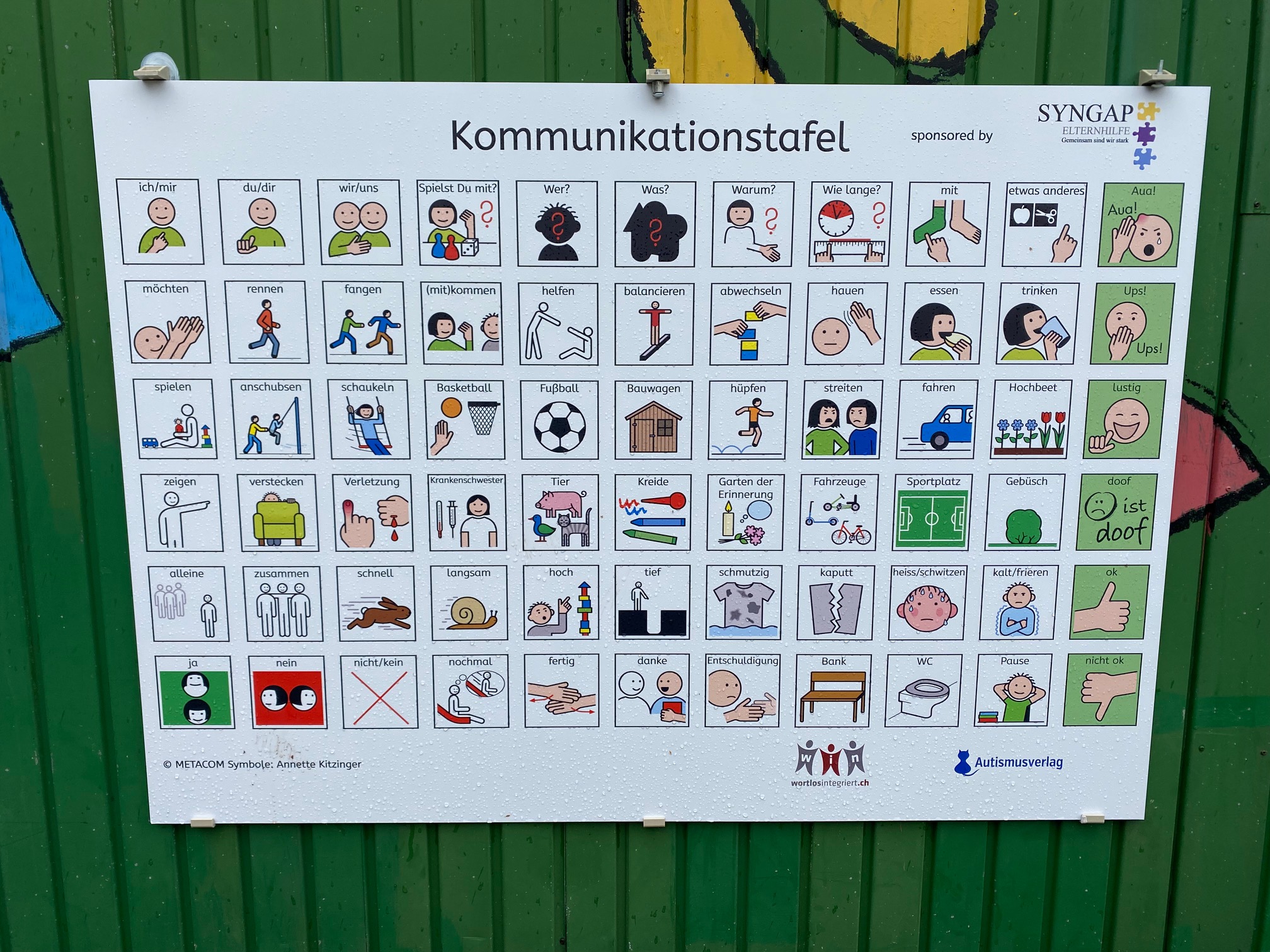 Spielplatztafel an grünem Bauwagen auf Schulhof