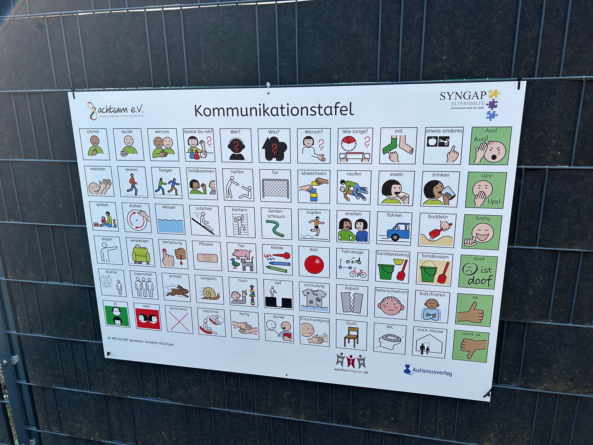 Spielplatztafel mit METACOM Symbolen an Metallzaun