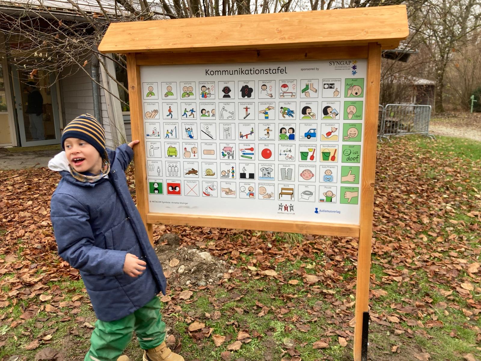 Junge zeigt auf Spielplatztafel mit METACOM Symbolen